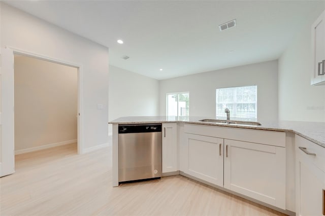 kitchen featuring light stone countertops, white cabinetry, sink, stainless steel dishwasher, and light wood-type flooring