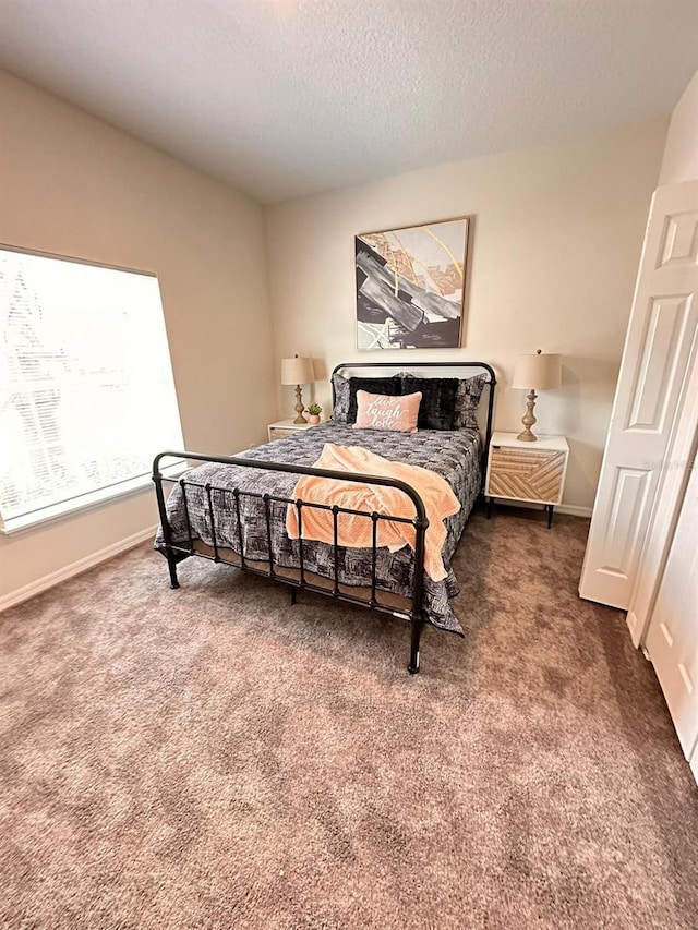 bedroom with dark colored carpet and a textured ceiling