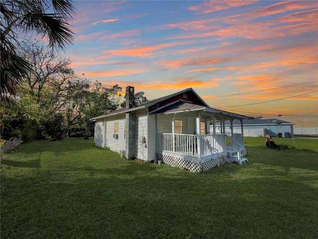 property exterior at dusk featuring a lawn and a porch