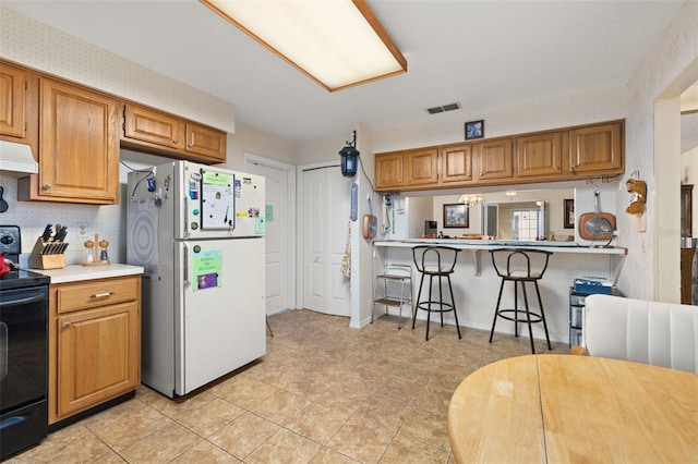 kitchen with kitchen peninsula, a kitchen breakfast bar, black range with electric cooktop, white refrigerator, and light tile patterned flooring