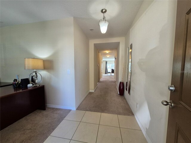 corridor featuring light colored carpet and a textured ceiling