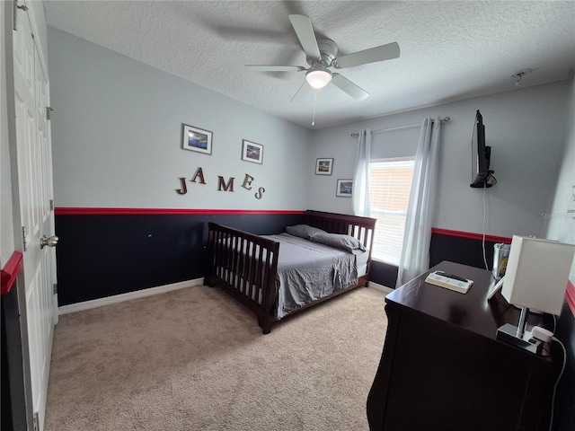 bedroom featuring ceiling fan, light colored carpet, and a textured ceiling