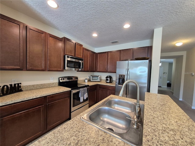 kitchen with dark brown cabinets, a textured ceiling, stainless steel appliances, and sink