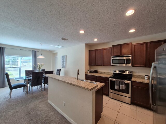 kitchen with hanging light fixtures, sink, stainless steel appliances, and a textured ceiling