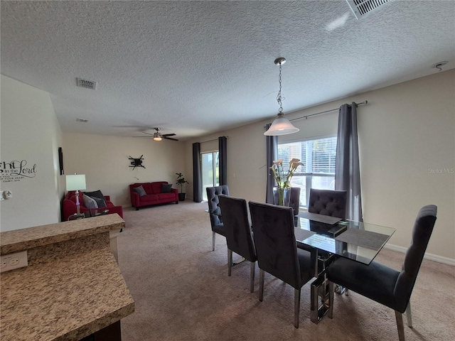 carpeted dining area featuring a textured ceiling and ceiling fan