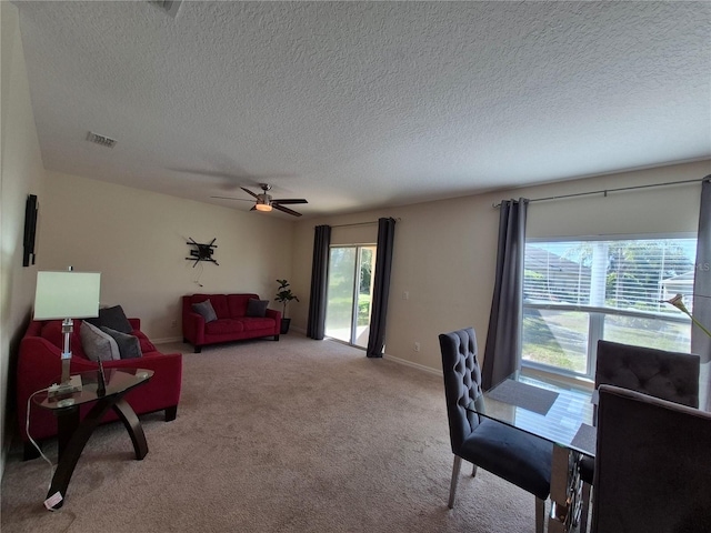 carpeted living room with a textured ceiling, a wealth of natural light, and ceiling fan