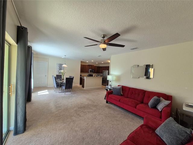 carpeted living room with a wealth of natural light, ceiling fan, and a textured ceiling