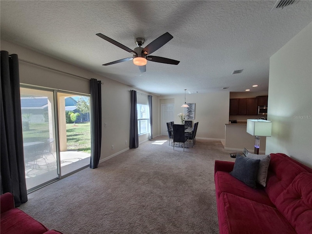 carpeted living room featuring a textured ceiling and ceiling fan