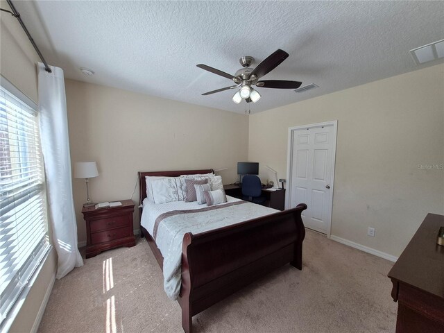 bedroom with ceiling fan, light carpet, and a textured ceiling