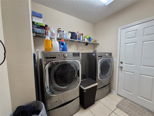 washroom with separate washer and dryer, light tile patterned floors, and a textured ceiling