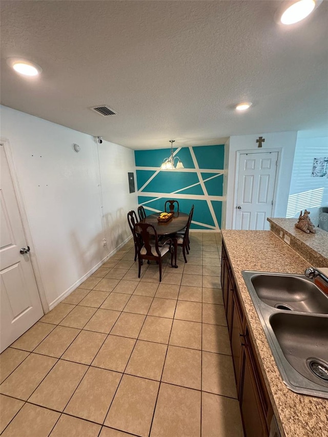 dining area with a textured ceiling, light tile patterned flooring, and sink