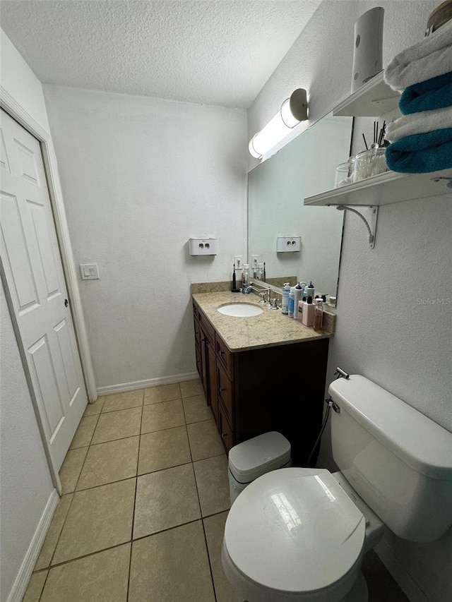 bathroom with tile patterned floors, vanity, a textured ceiling, and toilet