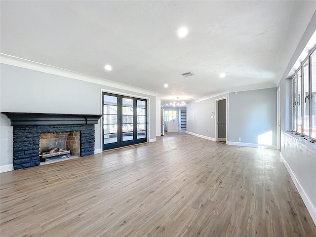 unfurnished living room with ornamental molding, light hardwood / wood-style flooring, a fireplace, and french doors