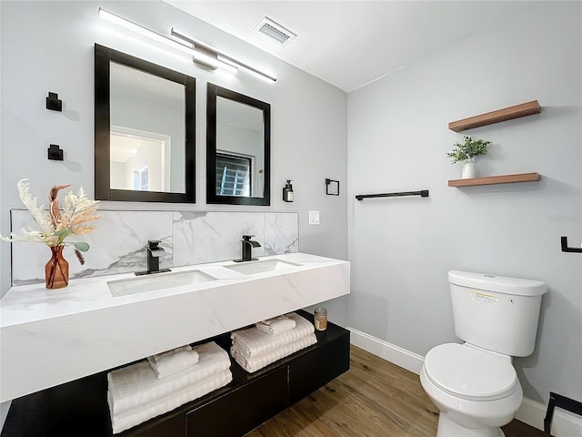 bathroom featuring vanity, decorative backsplash, wood-type flooring, and toilet