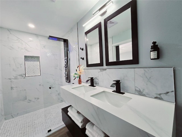 bathroom featuring tiled shower, vanity, and decorative backsplash