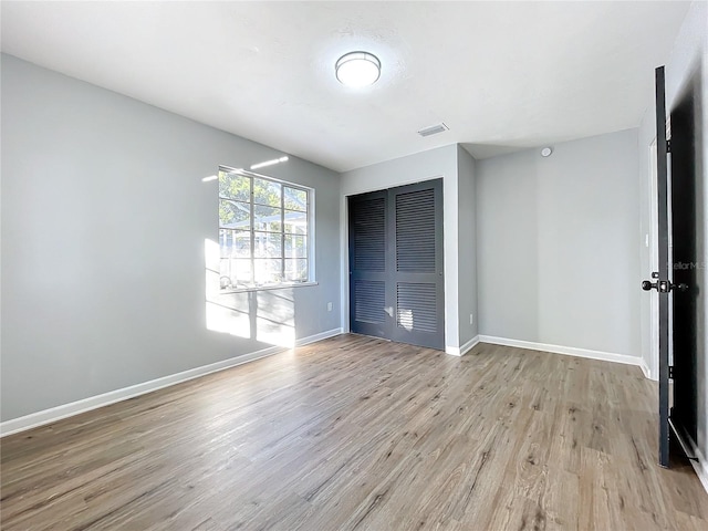 unfurnished bedroom with light wood-style flooring, baseboards, visible vents, and a closet