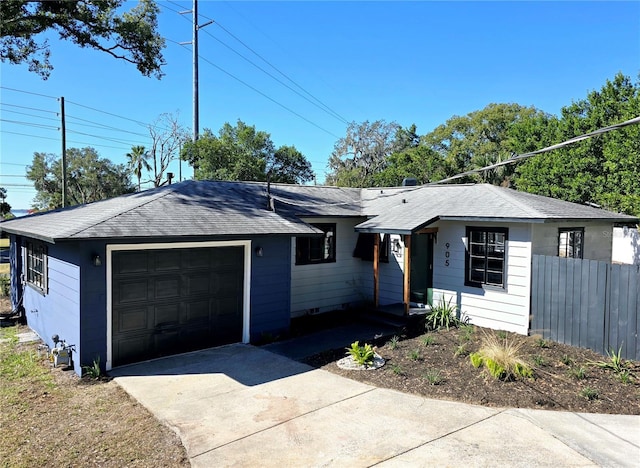 ranch-style home with a garage, a shingled roof, concrete driveway, and fence