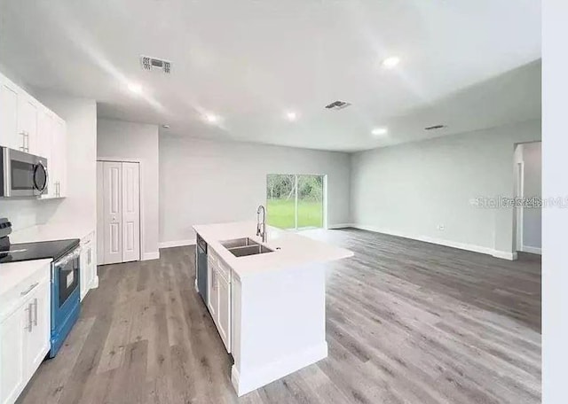 kitchen with white cabinetry, sink, hardwood / wood-style floors, an island with sink, and appliances with stainless steel finishes