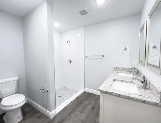 bathroom with walk in shower, hardwood / wood-style floors, vanity, and toilet