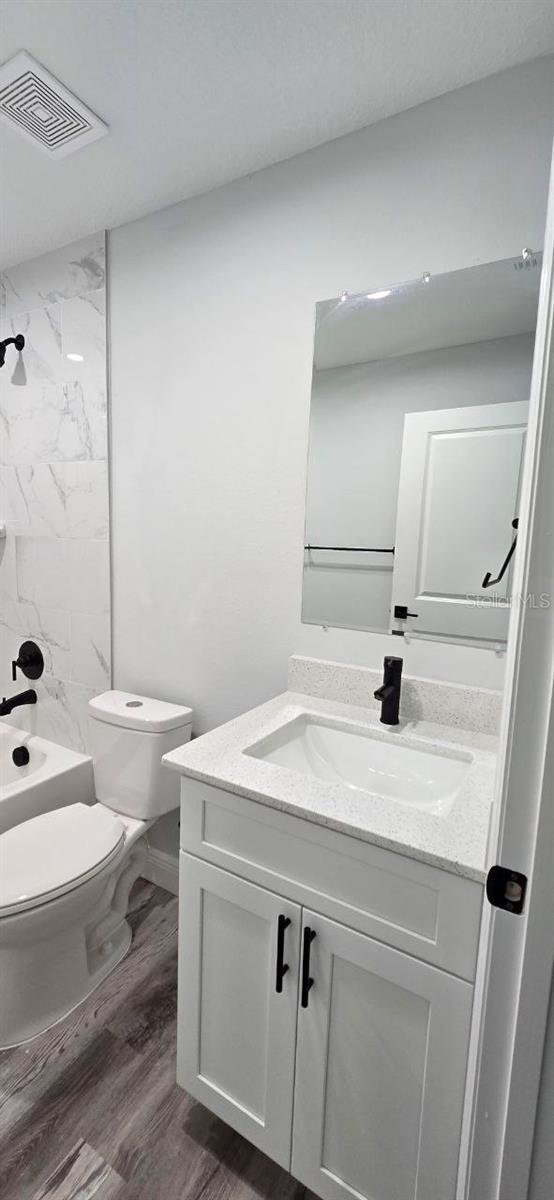 1030 Darlington Ct, Kissimmee, FL 34758 - full bathroom featuring vanity and wood finished floors