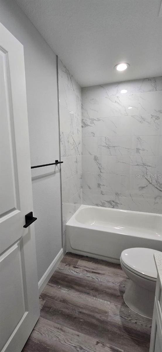 1030 Darlington Ct, Kissimmee, FL 34758 - bathroom with vanity, wood finished floors, recessed lighting, washtub / shower combination, and a textured ceiling