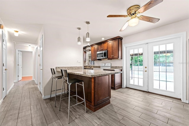 kitchen featuring kitchen peninsula, french doors, light wood-type flooring, ceiling fan, and hanging light fixtures