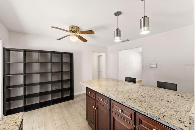 kitchen with light stone countertops, ceiling fan, and hanging light fixtures