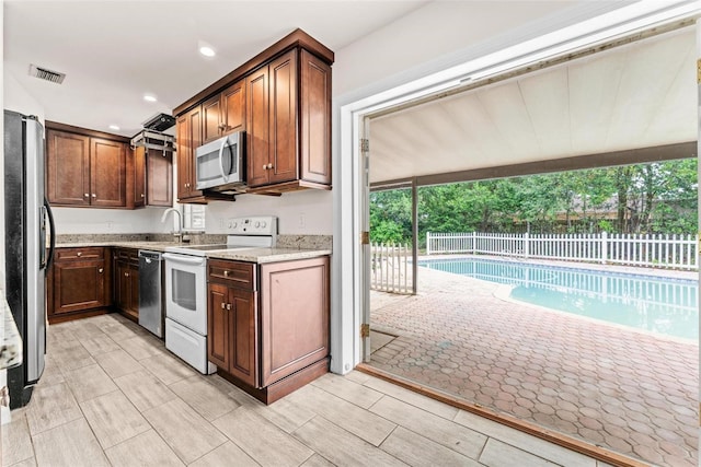 kitchen with light stone countertops, sink, and stainless steel appliances