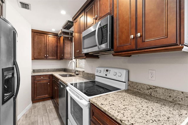 kitchen featuring ventilation hood, sink, light hardwood / wood-style flooring, light stone countertops, and stainless steel appliances