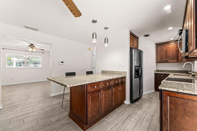 kitchen with ceiling fan, a kitchen breakfast bar, light hardwood / wood-style flooring, pendant lighting, and appliances with stainless steel finishes