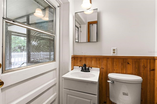 bathroom with wooden walls, vanity, and toilet