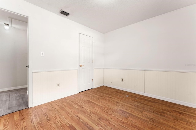 empty room with wood-type flooring and a textured ceiling