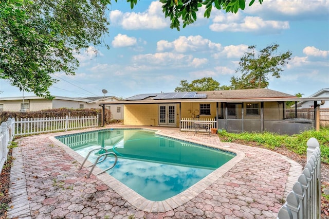 view of swimming pool featuring a sunroom, a patio area, and french doors