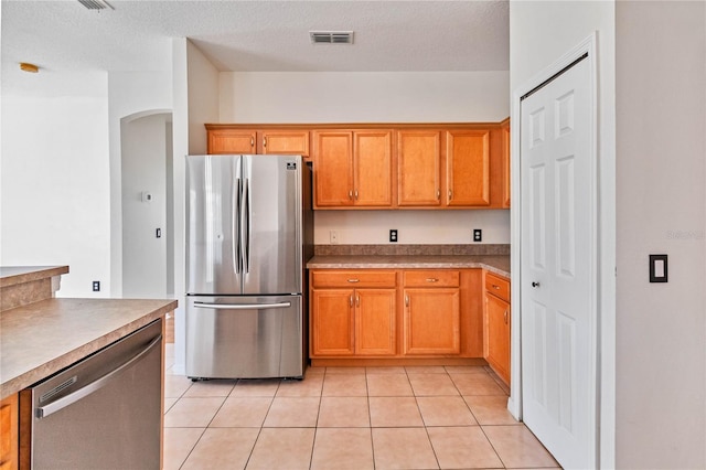 kitchen featuring appliances with stainless steel finishes, a textured ceiling, and light tile patterned floors