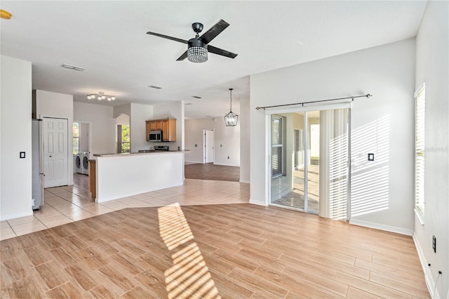 unfurnished living room featuring ceiling fan with notable chandelier and independent washer and dryer