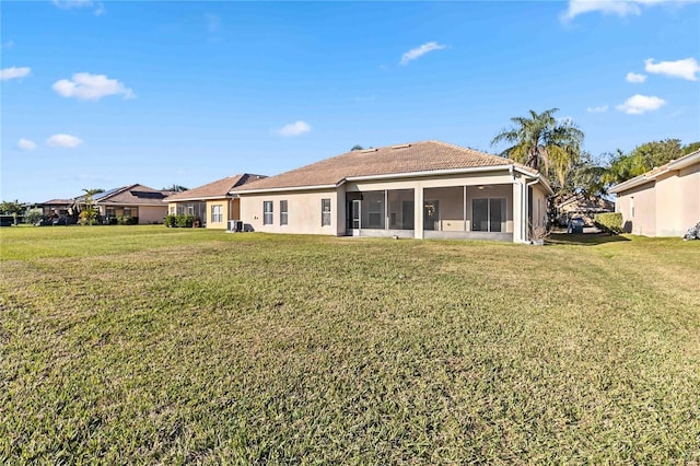 rear view of property featuring a lawn and a sunroom