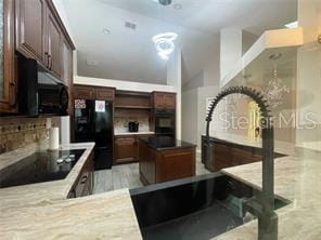 kitchen featuring black appliances, decorative backsplash, and dark brown cabinetry