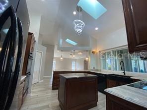 kitchen with sink, a chandelier, light hardwood / wood-style floors, a kitchen island, and hanging light fixtures