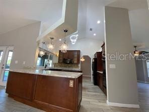 kitchen with ceiling fan, light wood-type flooring, kitchen peninsula, and hanging light fixtures