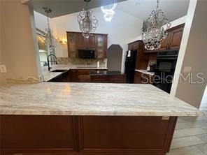 kitchen featuring kitchen peninsula, vaulted ceiling, sink, black appliances, and pendant lighting