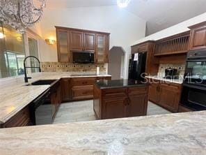 kitchen featuring tasteful backsplash, light stone counters, vaulted ceiling, sink, and black appliances