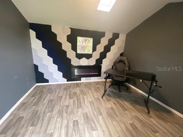 office area with vaulted ceiling with skylight and hardwood / wood-style floors