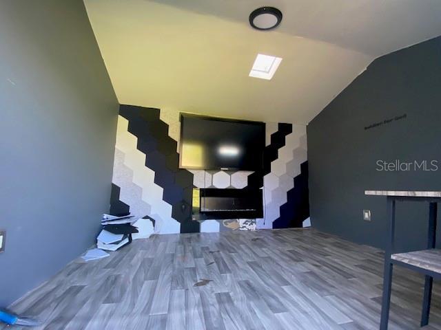 interior space with wood-type flooring and lofted ceiling with skylight