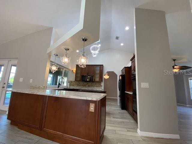 kitchen featuring high vaulted ceiling, hanging light fixtures, ceiling fan, light wood-type flooring, and kitchen peninsula