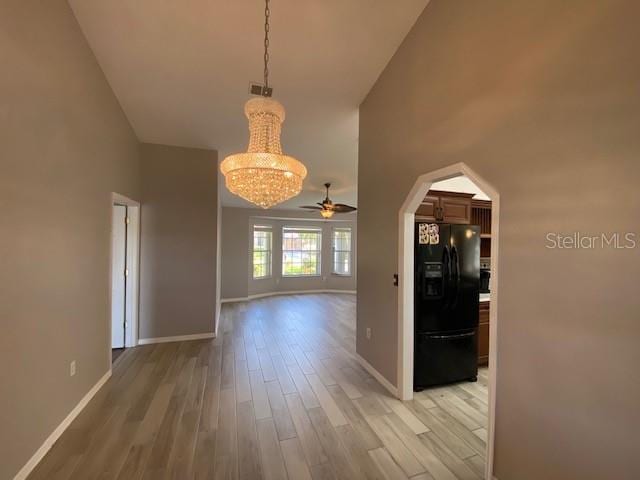 interior space featuring ceiling fan with notable chandelier, light hardwood / wood-style floors, and a towering ceiling