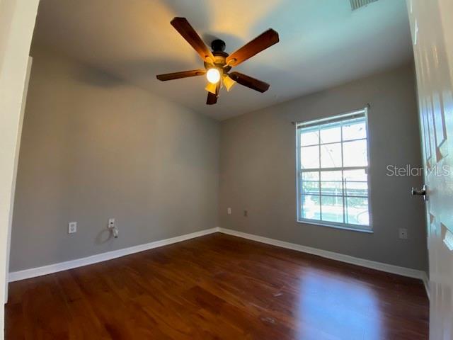 unfurnished room with ceiling fan and dark hardwood / wood-style flooring