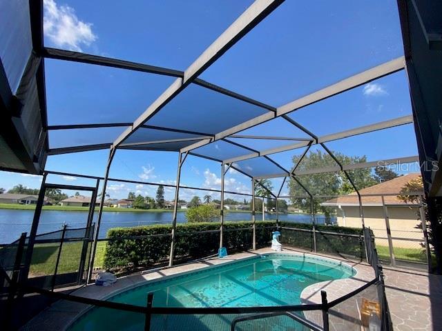 view of swimming pool with a patio, a water view, and a lanai