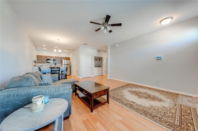 living room featuring light hardwood / wood-style flooring and ceiling fan with notable chandelier