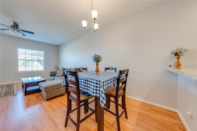 dining space featuring light hardwood / wood-style flooring and ceiling fan with notable chandelier