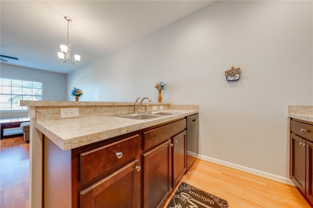 kitchen featuring dishwasher, an inviting chandelier, sink, light wood-type flooring, and decorative light fixtures